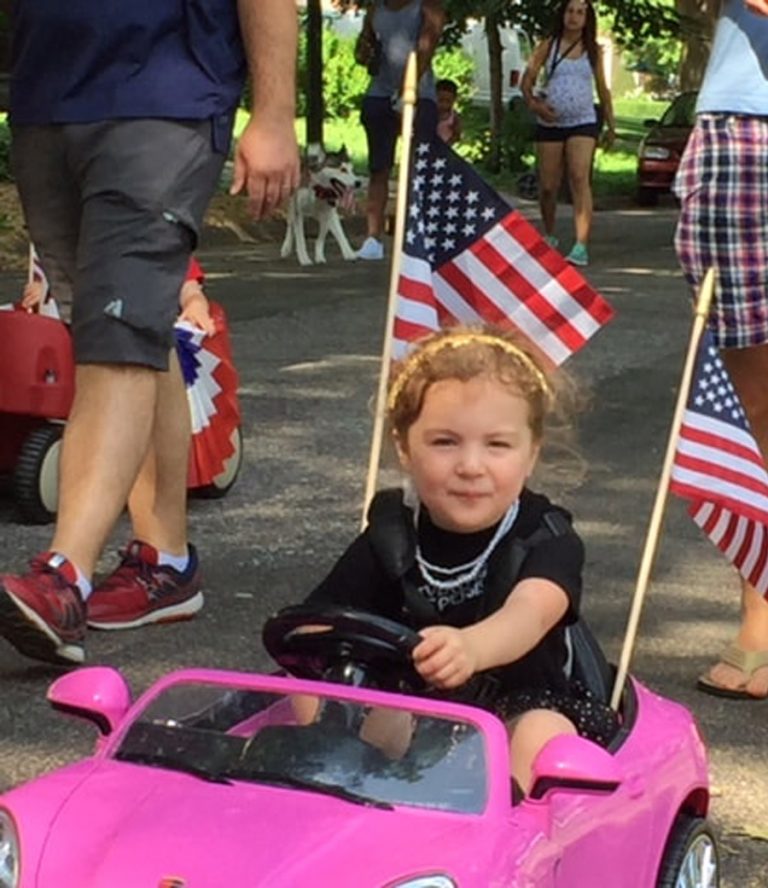 East Campus young girl in pink car with flags 4th of July parade
