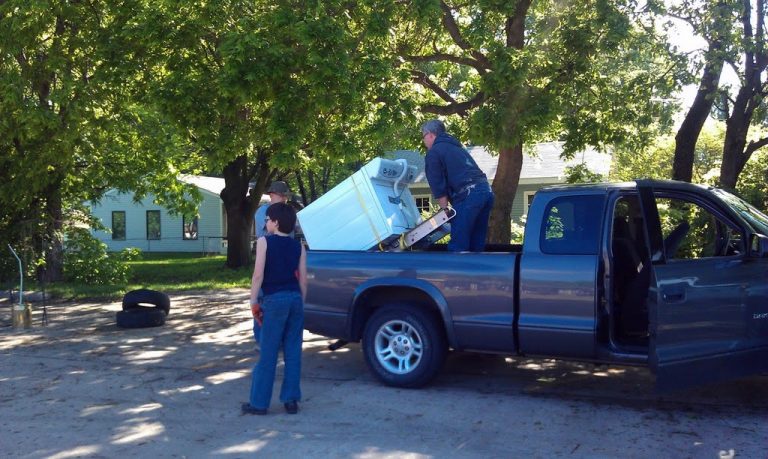 Discarded washing machine being loaded on a pickup truck