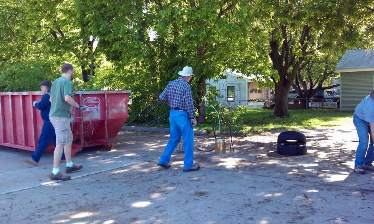 People filling a large dumpster