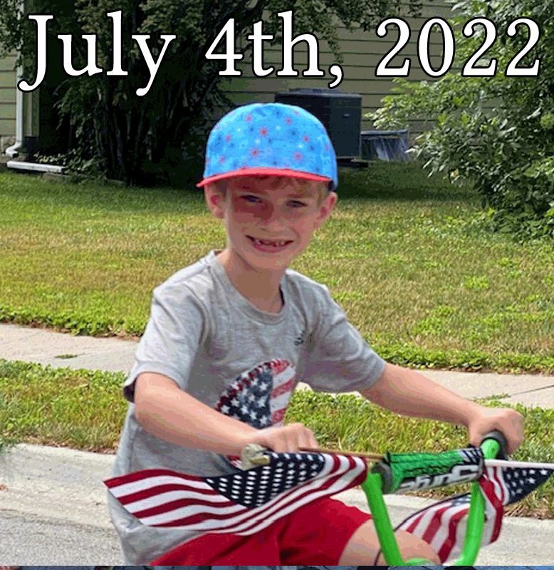 July 4 2022 gallery heading with boy smiling from a bicycle decorated with numerous flags